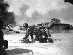 Two US Marines crawling into position on a Saipan, Mariana Islands beach after their landing craft was hit by Japanese mortar, 15 Jun 1944; note LVT(A)-4 Water Buffalo in background