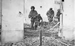 Four British paratroopers with Sten sub-machineguns moving through a shell-damaged house in Oosterbeek, the Netherlands to which they had retreated after being driven out of Arnhem, 23 Sep 194