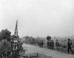 Infantry of British 50th (Northumbrian) Division moving up past a knocked-out German 88mm gun near 
