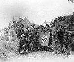 American troops posing with a captured Nazi flag and a wrecked German tank, Chambois, France, 20 Aug 1944
