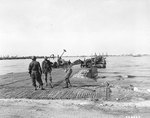 American soldiers constructing a landing ramp as part of the Mulberry A artificial harbor at Omaha Beach, Normandy, circa mid-Jun 1944