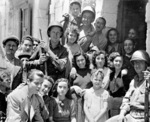 US Army Private George Katere, Private First Class William Mosa, and Private First Class Jessie Hampton posing with Sicilian civilians, Italy, 11 Jul 1943