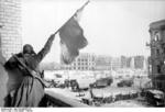 Soviet soldier waving a red flag at a building off the central square in Stalingrad, Russia, Jan-Feb 1943