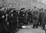 SS personnel guarding rounded-up Jews in the Warsaw ghetto, Poland, Apr-May 1943