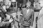 Polish resistance fighter Captain Cyprian Odorkiewicz holding a German Army cap, Okólnik gardens, Warsaw, Poland, 14 Aug 1944; note captured MP 40 submachine gun