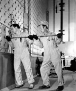 Workers using a rod to push uranium slugs into the loading face of the X-10 graphite reactor, Oak Ridge, Tennessee, United States, date unknown