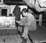 USAAF 3rd Bomb Group photographer Jack Heyn reading at his bunk, Dobodura Airfield, Australian Papua, mid-1943