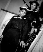 Two African-American USCG SPARS, Olivia Hooker and Aileen Anita Cooks, posing on a ladder aboard training ship 