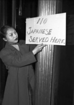 Chinese-American Gertrude Moy posting anti-Japanese sign outside the Hoe Sai Gai restaurant where she was employed, Chicago, Illinois, United States, Dec 1941