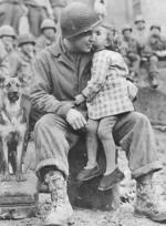 US Army Signal Corp Photo Tec-4 Elvin Harley getting a kiss from a French child while listening to the US 9th Armored Division Band near Aboncourt, France, 14 Feb 1945