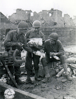 US Army Pfc. Carl Anker, Pfc. Edmund Dill, and Sgt. Ted Bailey sharing the contents of the care package sent by Dill