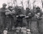US Army Pfc. W. J. Kessler, Pfc. J. L. Proffitt, Pvt. B. Narter, Cpl. T. J. Barnewski, and Pfc. J. Stoll handling Christmas packages from home for their artillery unit, Germany, 26 Nov 1944