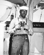 US Navy African-American Seaman 2nd Class Napoleon Reid standing on lookout on a ship in the Pacific Ocean, 19 Mar 1945