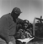 African-American pilot of US 332nd Fighter Group signing the Form One Book, indicating any discrepancies of aircraft, prior to take off, Italy, Mar 1945