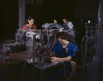 Employees of American Aviation, Inc. working with sheet metal, Inglewood, California, United States, Oct 1942; note woman working on pneumatic numbering machine