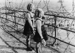 Two British girls looking beyond barbed wire obstacles on the southern coast of England, United Kingdom, date unknown