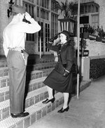WAVES Ensign Emma D. Shelton received salute from a US Marine sentry s she enters an apartment building that served as temporary WAVES quarters, circa 1943