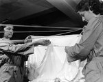 WAVES Parachute Riggers carefully folding silk fabric, while packing a parachute at a Naval Air Station, United States, Nov 1943