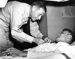 Vice Admiral Raymond Spruance awarding Purple Heart to USMC Corporal John K. Galuszka aboard a hospital ship, Pearl Harbor, Hawaii, 17 Dec 1943. Corporal Galuszka had been wounded during the Gilberts Operation.