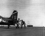 John Arledge and Theodore Schmidts unhooking a F4F fighter from the arresting cable aboard USS Anzio, Pacific Ocean, 21 Apr 1945