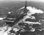 Essex taking spray over the bow while steaming in heavy seas, 12 Jan 1960; note S2F aircraft at rear of flight deck with engine turning, and AD and F4D aircraft at rest