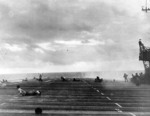Flight deck crew of USS Langley ducking as a Japanese aircraft attacked the carrier (seen in center of photo), off Taiwan, 14 Oct 1944