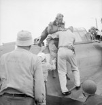 SBD Dauntless crewman Alva Parker, having suffered neck and shoulder shrapnel wounds over Rabaul, New Britain, being helped from the aircraft after landing on USS Saratoga, 5 Nov 1943