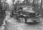 US Army 2 1/2-ton 6x6 cargo truck towing a piece of field artillery through heavy mud in the South Pacific, date unknown; bumper markings showed 98th Division, 369th Field Artillery