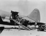 A Jeep being loaded into the sizeable fuselage of a C-46 Commando cargo plane, while another waited to be driven up the ramp, Mar 1942