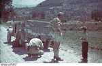 German soldiers speaking with a Sicilian boy as they changed a tire on their Kübelwagen, Sicily, Italy 1943