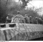 German paratroopers aboard a camouflaged SdKfz. 251 halftrack vehicle in an Italian town, 1944