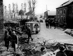 Jeeps, Dodge WC54 3/4-ton field ambulances, and US troops on a street in the heavily damaged town of Foy, Belgium, 16 Jan 1945
