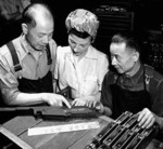 Chinese technicians Louie Ha (left) and Wong Lim (right) speaking with Canadian factory worker Sophie Nicolak about the Chinese inscription on a newly made Bren gun, John Inglis and Company factory, Toronto, Canada, 1940s
