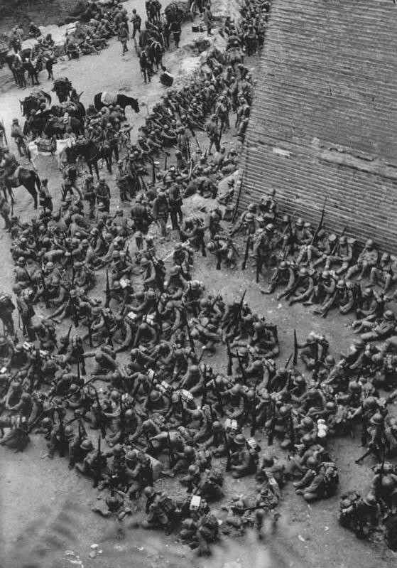 Japanese soldiers resting at the base of the old city wall, Baoding, Hebei, China, circa late 1937 to early 1938