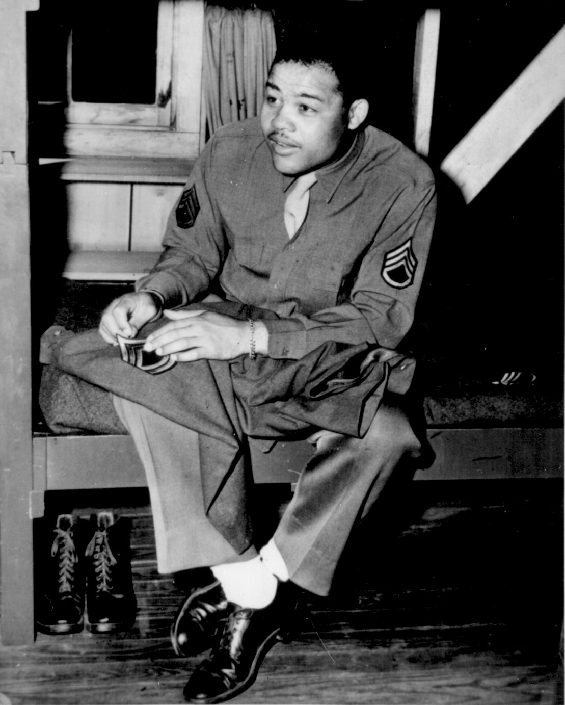 African-American boxing champion and US Army Technical Sergeant Joe Louis sewing his rank patch onto his uniform, 10 Apr 1945