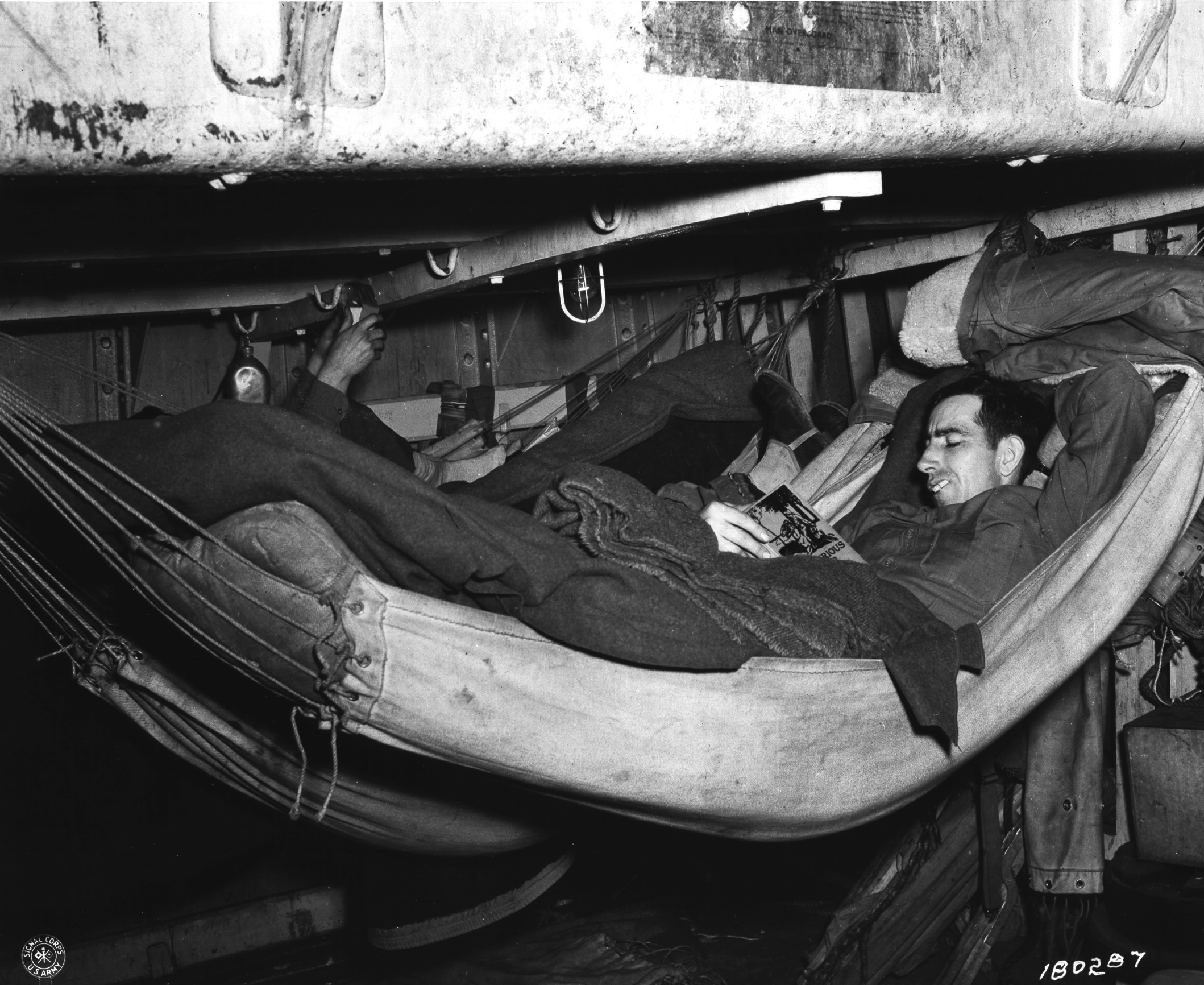US Army soldier relaxing with a book while aboard a transport, off Iceland, 20 May 1943