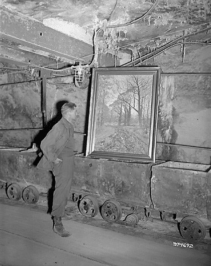 US Army Corporal Donald Ornitz examining a looted painting in the Merkers salt mine, Germany, Apr 1945