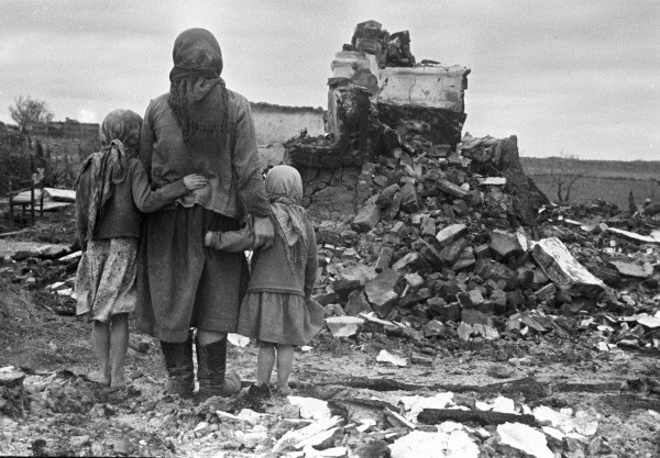 Russian mother and children looking at a destroyed home, Russia, 1 Sep 1943