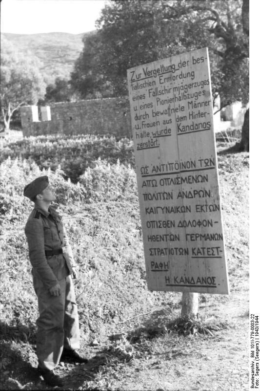 Dual-language sign noting that the village of Kaldanoss in Greece was destroyed in retaliation for the killing of German troops, 1943-1944