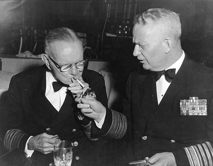 Admiral Burke lighting a cigarette for Fleet Admiral Halsey, probably New York City, circa mid- or late-1950s