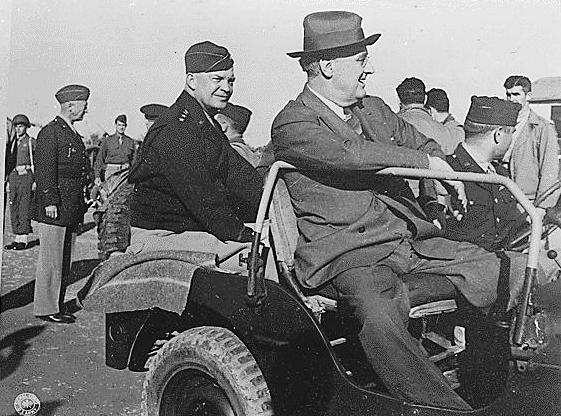 Franklin Roosevelt with Dwight Eisenhower at Castelvetrano Airport in Sicily, Italy, after the conferences at Tehran and Cairo, 8 Dec 1943; note Patton in background