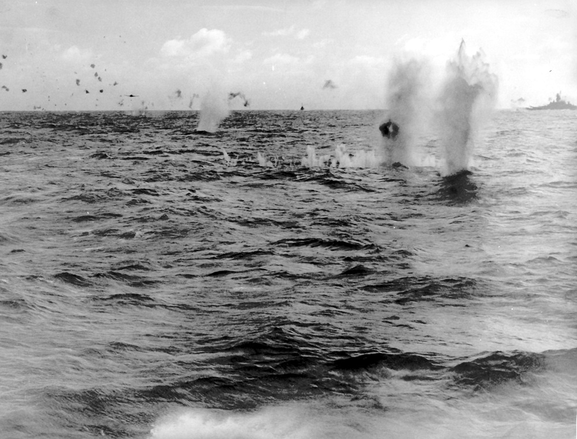 Japanese B6N aircraft releasing a torpedo in waters between Taiwan and Philippine Islands, 14 Oct 1944; USS Alabama and a destroyer in background; photo taken from USS Essex