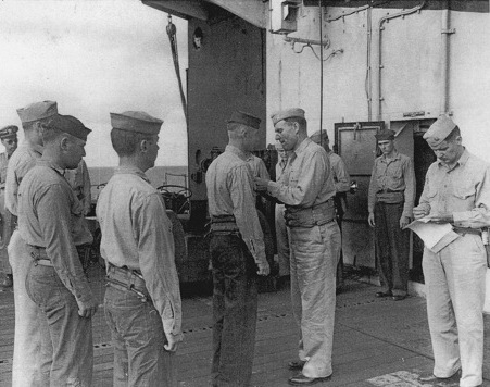 Captain George C. Montgomery awarding a citation ribbon to Aviation Ordnanceman 2nd Class Harvey J. Rowe aboard USS Anzio, 6 Jan 1945, photo 1 of 2