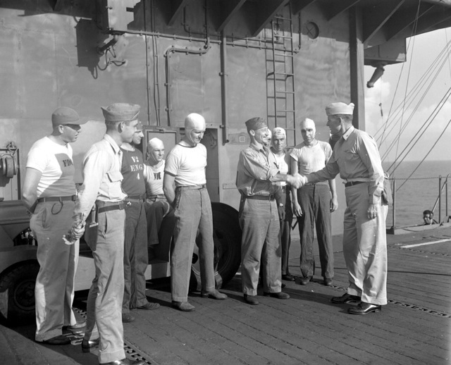 Captain George C. Montgomery shaking hands with men under his command aboard USS Anzio, 23 May 1945