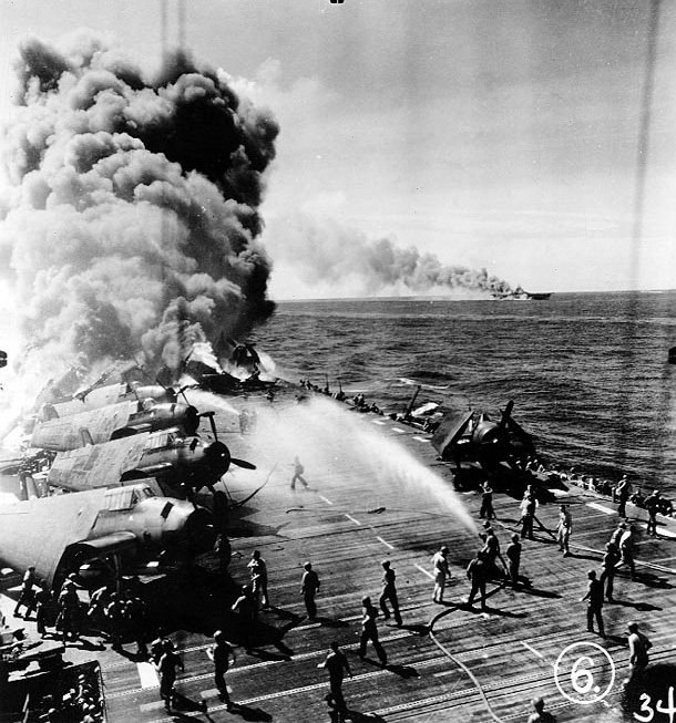 Firefighters of Belleau Wood fighting flames caused by a special attack aircraft, in the Philippine Islands, 30 Oct 1944; note TBM Avenger aircraft on flight deck and Franklin burning in distance. Photo 1 of 2