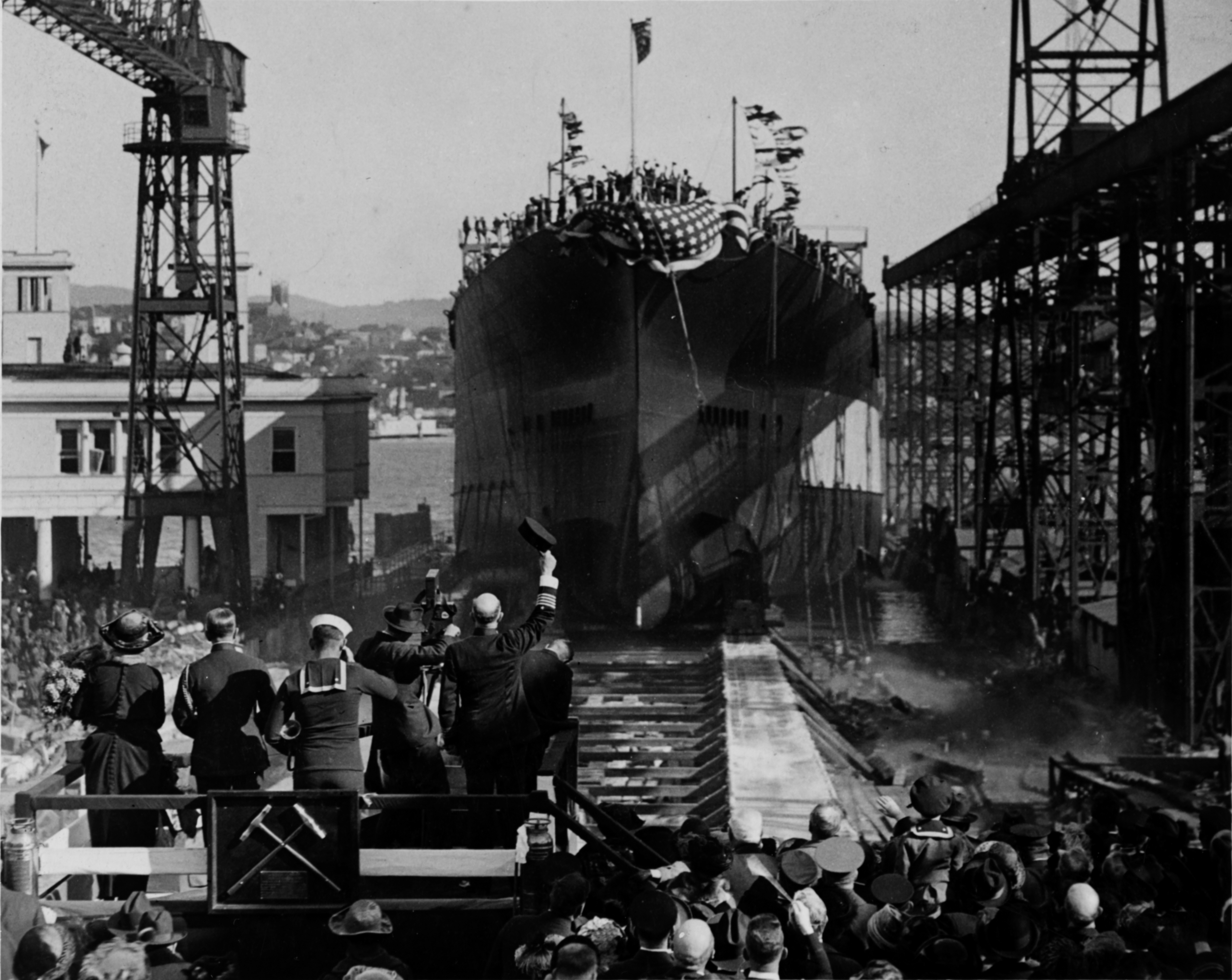 Launch of USS California at Mare Island Navy Yard, 20 Nov 1919; note the sponsor Mrs. R. T. Zane (left, woman with hat), a bugler (center), a motion picture camera with its operator, and a US Navy captain (waving hat) on the platform