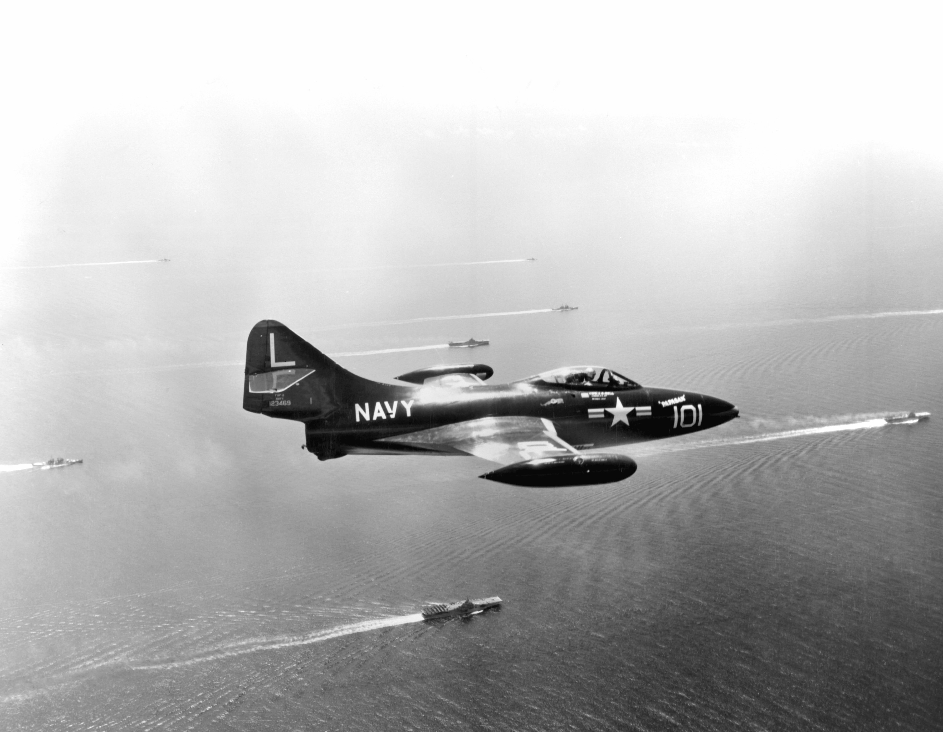F9F-2 Panther fighter flying over carriers USS Bon Homme Richard, USS Essex, and USS Princeton off Korea, 1 Aug 1952