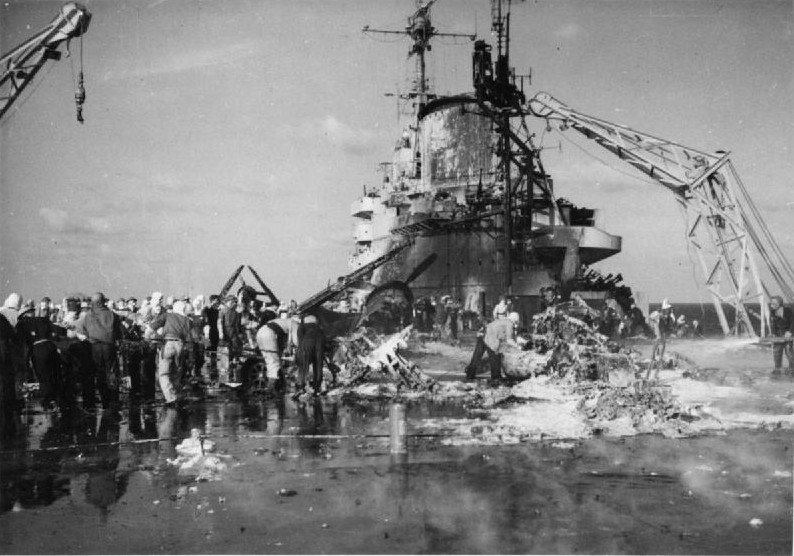 HMS Formidable crewmen starting to remove the wreckage of Japanese special attack aircraft from the flight deck, Pacific Ocean, 4 May 1945