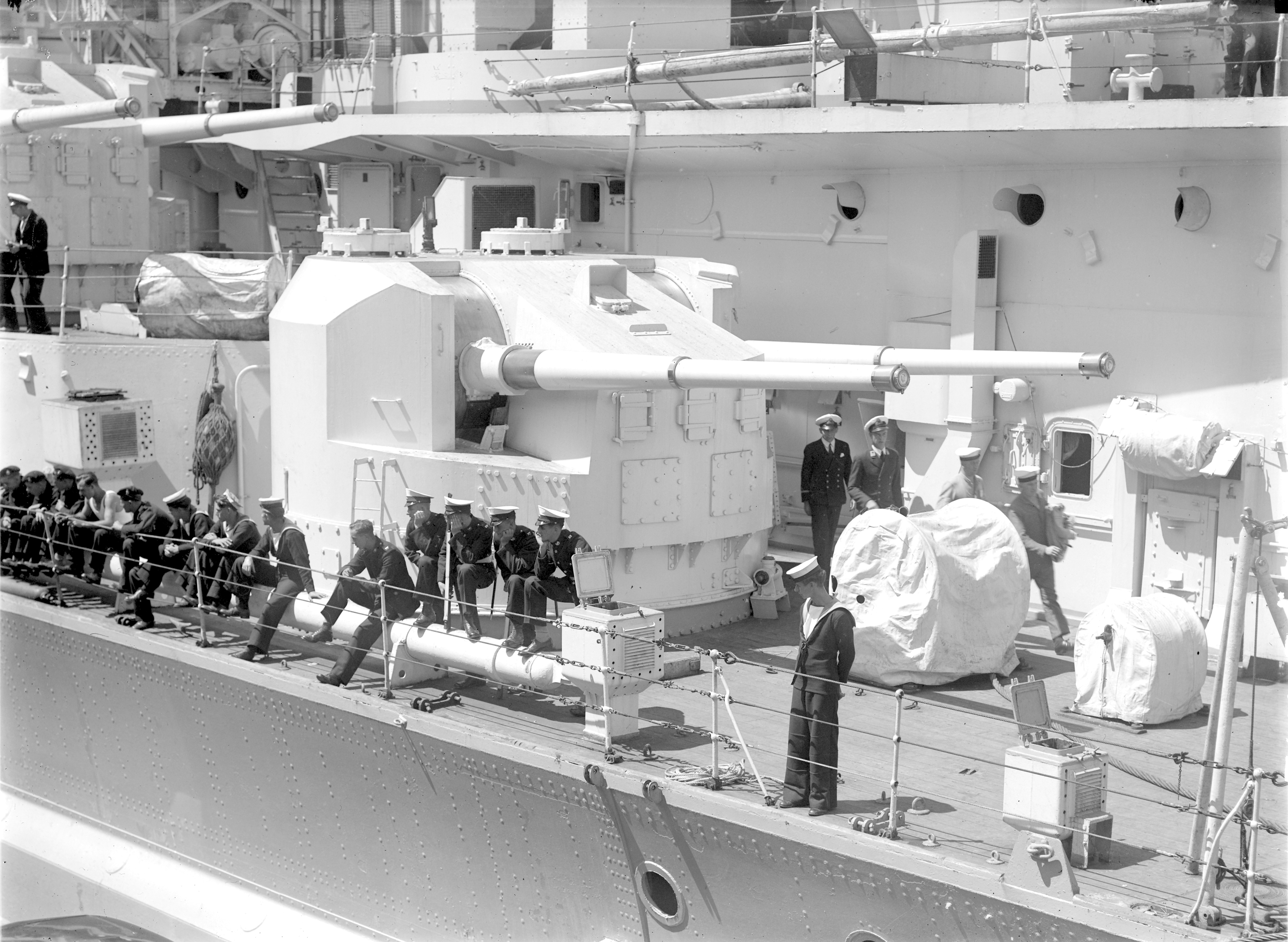 Close-up of one of HMS King George V's secondary gun turrets and various officers and crew, 1945