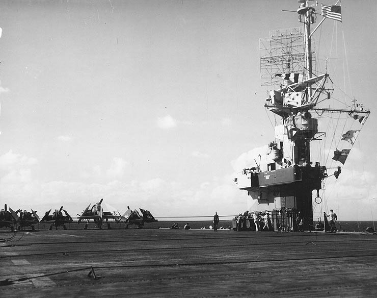 USS Makin Island's flight deck and island, late 1944-mid 1945; note arresting wires, barrier wires, 4 FM-2 Wildcat aircraft, and 1 TBM Avenger aircraft